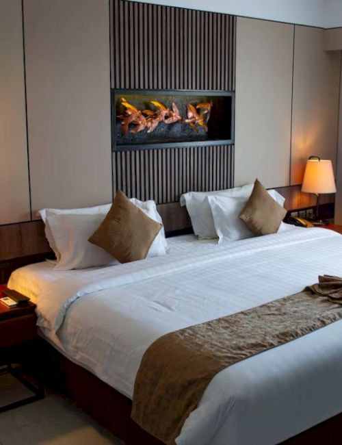 A neatly arranged hotel room with a king-size bed, two bedside tables with lamps, and a decorative wall panel above the bed.