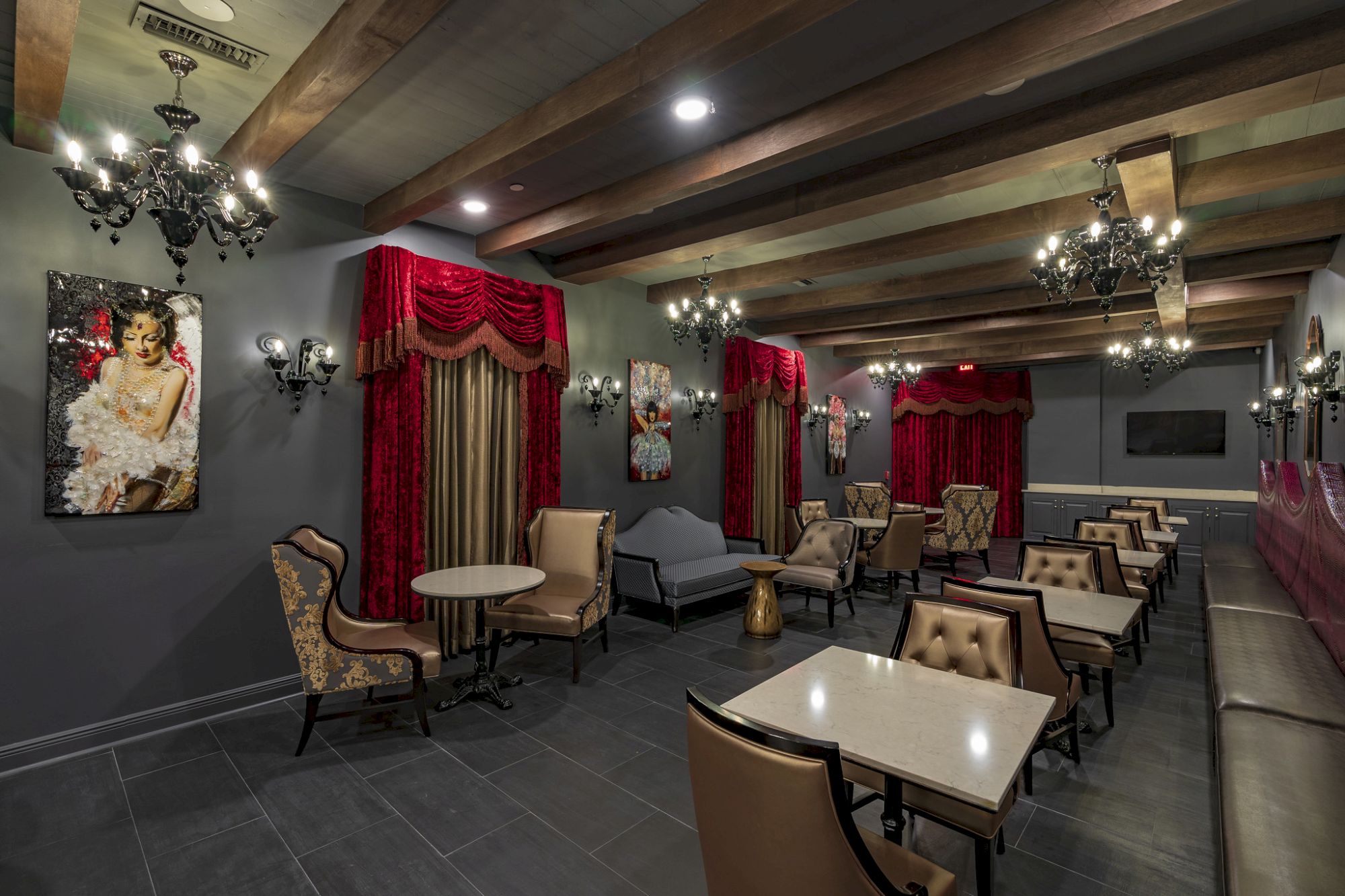 An elegant dining area with red curtains, cushioned chairs, chandeliers, and art on the walls, creating a classic, sophisticated ambiance.