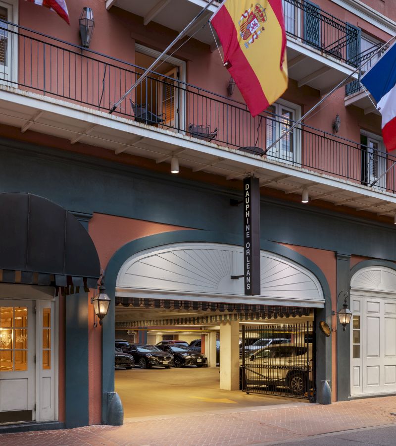 The exterior of a building with a balcony, flags, and a parking garage.