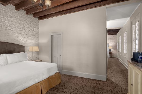 A cozy room with a large bed, brick walls, wooden beams, and elegant lighting, showcasing a peaceful and refined atmosphere.