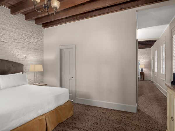 A cozy room with a large bed, brick walls, wooden beams, and elegant lighting, showcasing a peaceful and refined atmosphere.