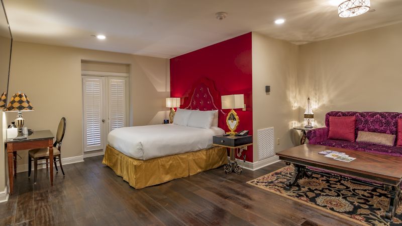 A wide view of a hotel room with a bed, couch, desk, and rug.