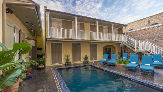 A pool with lounge chairs and a balcony in the background.