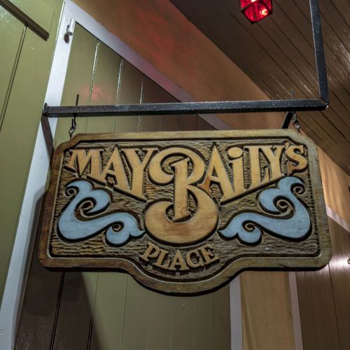 A wooden sign reading "May Baily's Place" hangs from a building, with a red lantern above it.