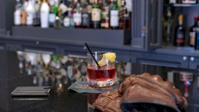 a cocktail on a bar with a brown leather bag