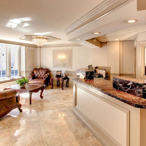 Luxurious hotel lobby with leather seating, elegant decor, marble flooring, chandelier, and a reception desk featuring a polished surface.
