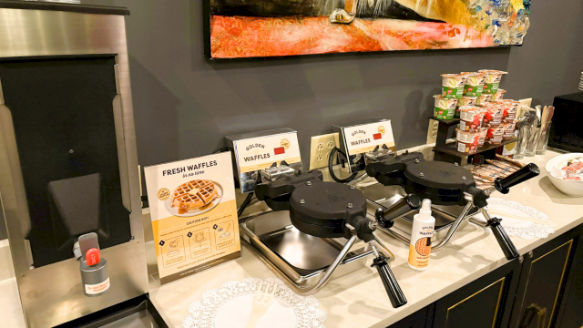 A breakfast buffet with waffle irons, yogurt, and coffee.