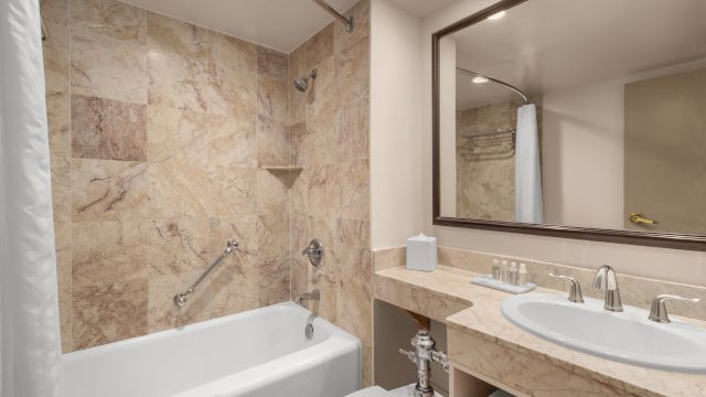 A bathroom with a bathtub, sink, and mirror