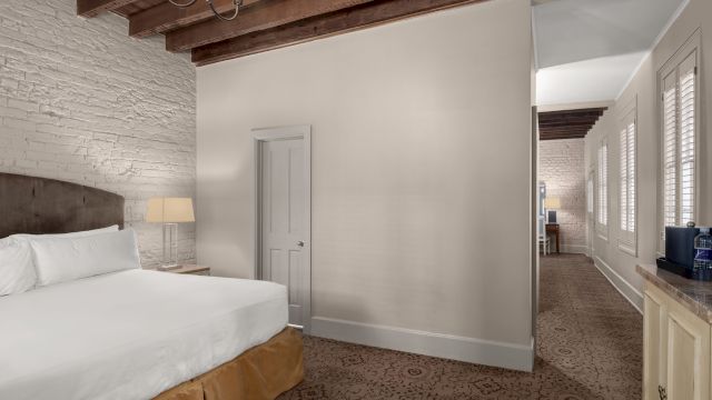 A hotel room with a bed, lamp, and door