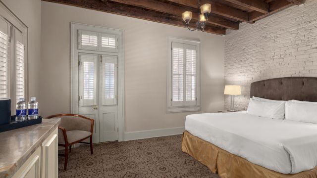 A wide view of a hotel room with a bed, chair, and lamp.