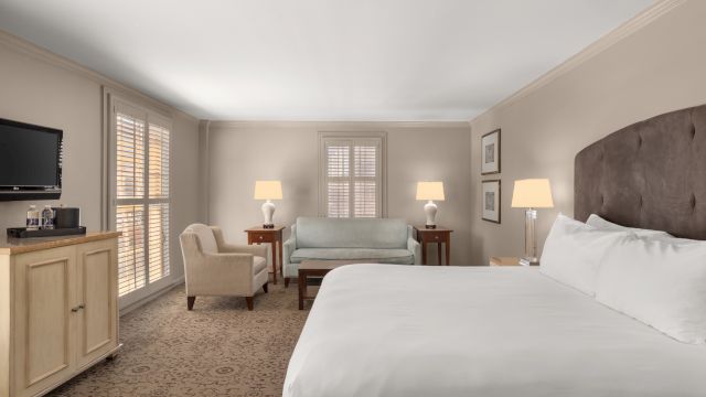 A hotel room with a large bed, seating area, and TV.