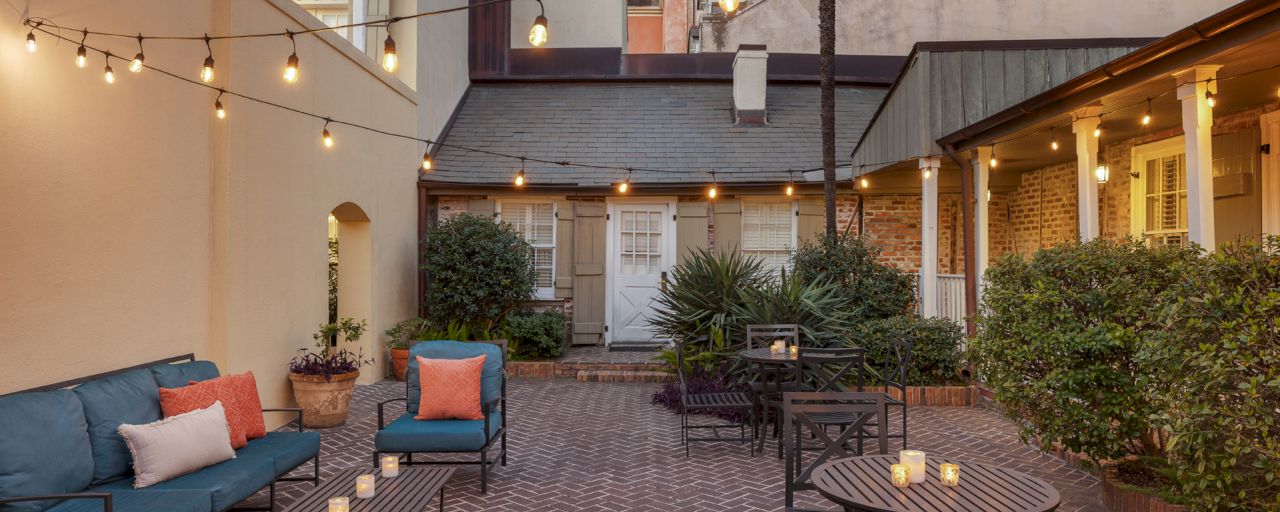 A cozy courtyard with a seating area, string lights, and potted plants.