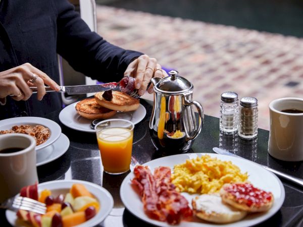 A person is preparing breakfast at a table with various dishes.