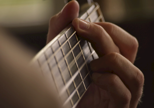 A person holds a small grid-like metallic device between their fingers, as if showing or adjusting it for a close-up.