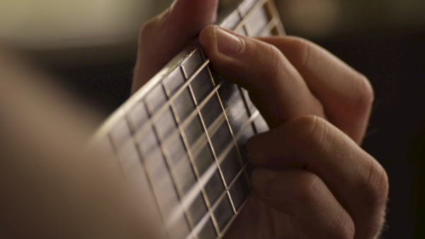 A person holds a small grid-like metallic device between their fingers, as if showing or adjusting it for a close-up.