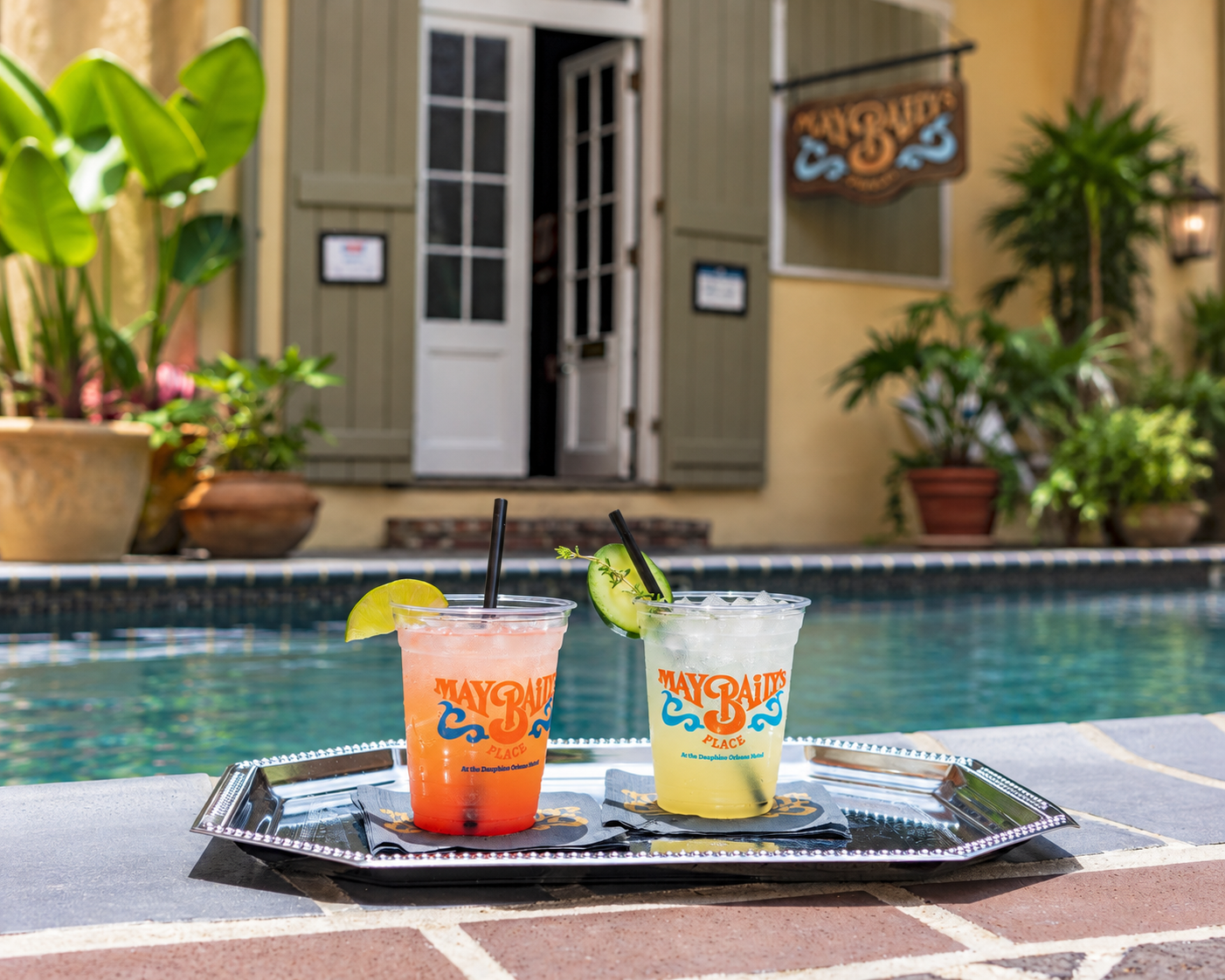 two drinks on a tray in front of a pool