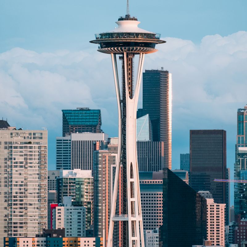 The image features the Space Needle with the Seattle skyline in the background under a clear sky.